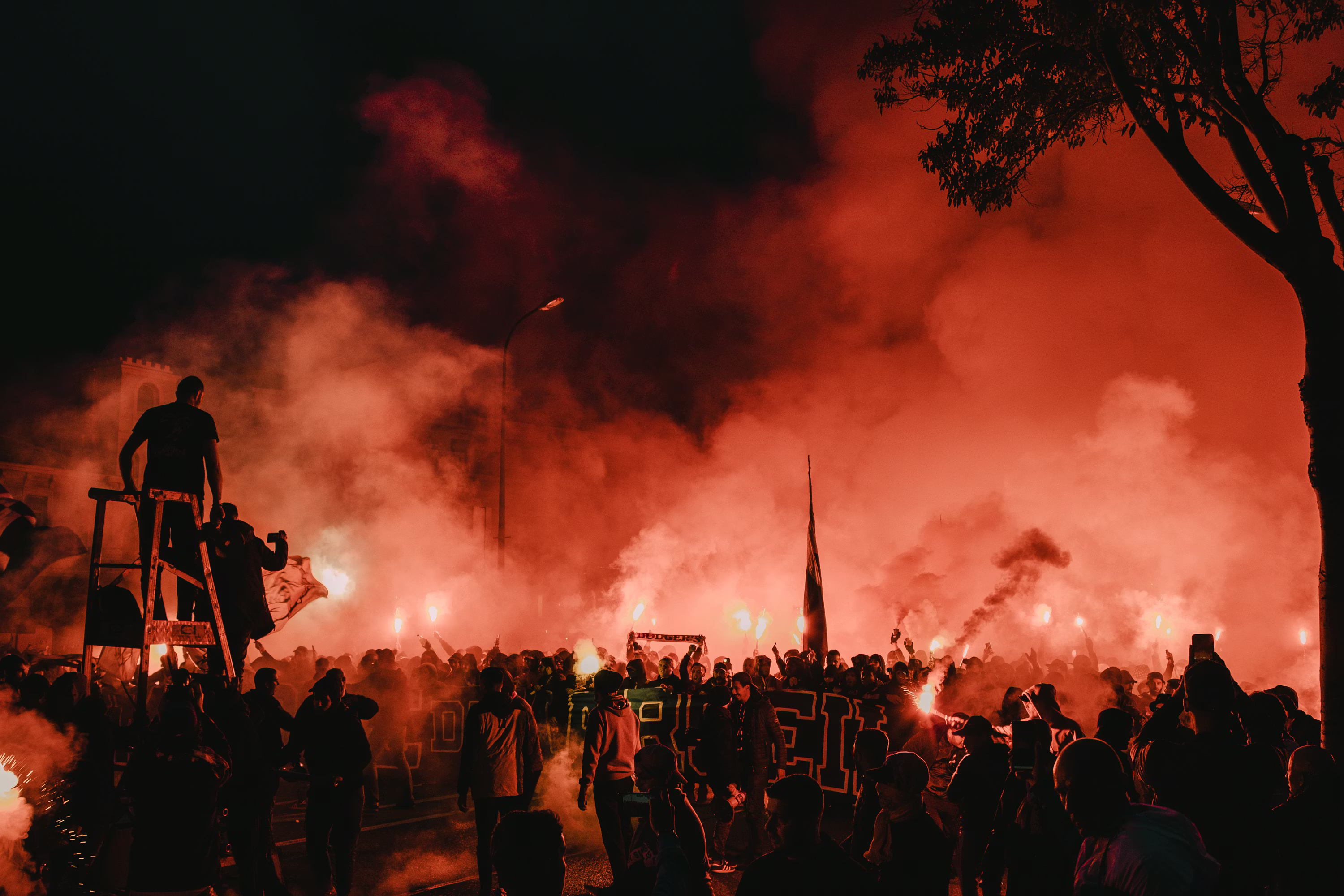 Ultras fans lighting flares in a packed stadium at night
